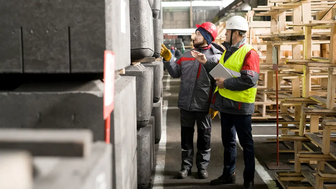 Técnicos inspeccionando bloques de grafito en estantería de almacén industrial