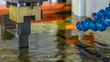 Graphite electrode in an EDM process submerged in dielectric fluid