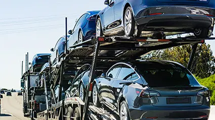 Tráiler porta-automóviles transportando vehículos eléctricos en una autopista